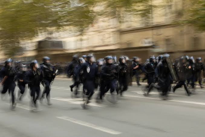 Des policiers en équipement de maintien de l'ordre se déplacent dans une rue