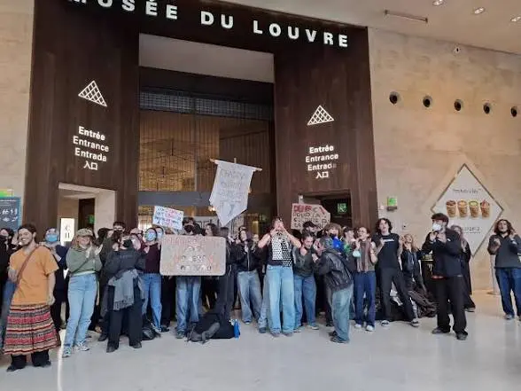 Des étudiants rassemblés avec des pancartes à l’entrée du musée du Louvre le 19 octobre 2026